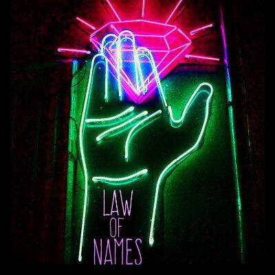 The Law of Names media logo, a neon sign of a green hand holding a bright pink diamond with Law of Names written underneath
